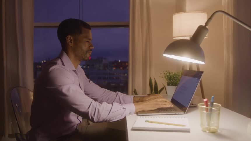 A man sits and types at his laptop