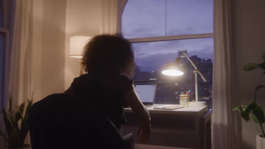 A woman walks over to and sits down at her desk