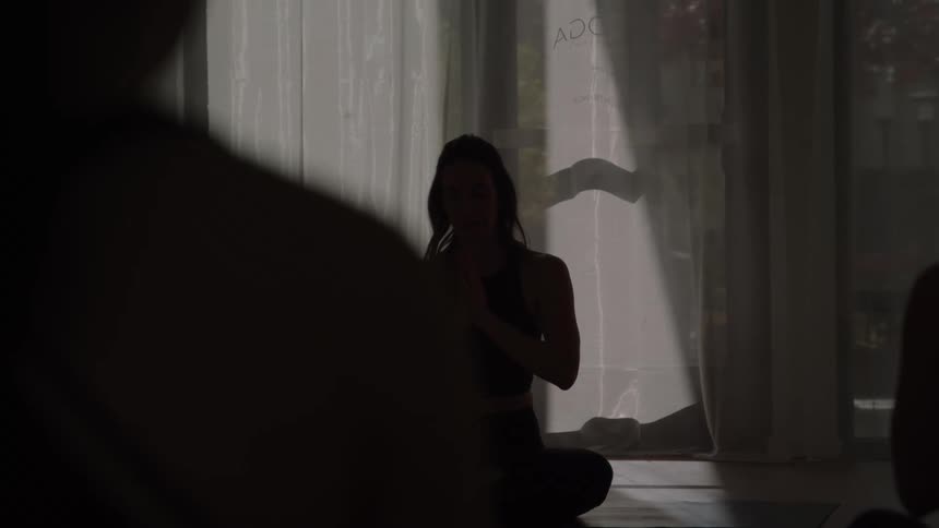 Female yoga instructor leads a class through a meditation session