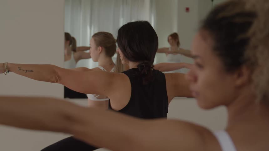 Women hold a balance pose with arms extended during a yoga class