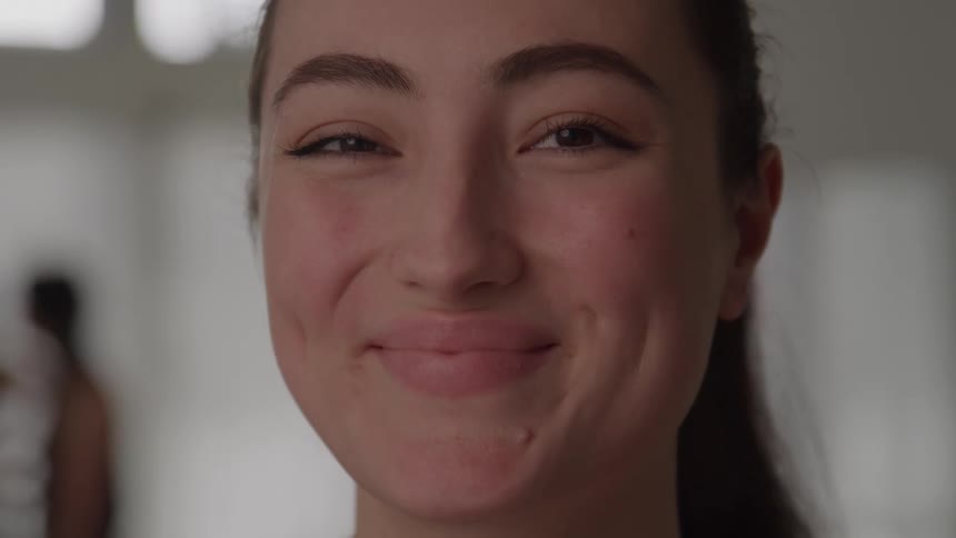 Woman smiles slightly while looking straight ahead in an indoor setting