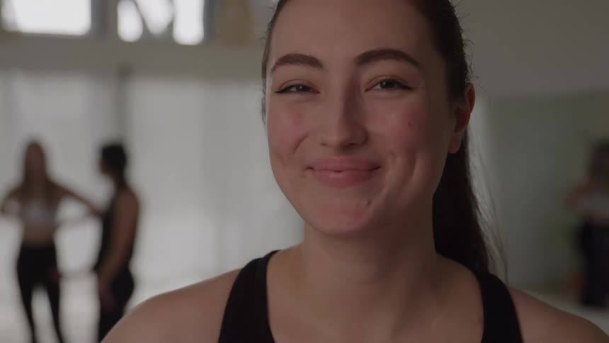 Woman smiles while standing in a yoga studio during a break in yoga class