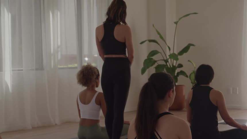 Instructor leads yoga practice with students seated in meditation posture