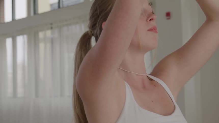 Woman raises her arms above her head during a yoga practice in a studio