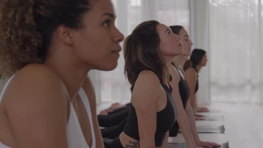 Group performs a stretching pose with raised torso during a yoga class