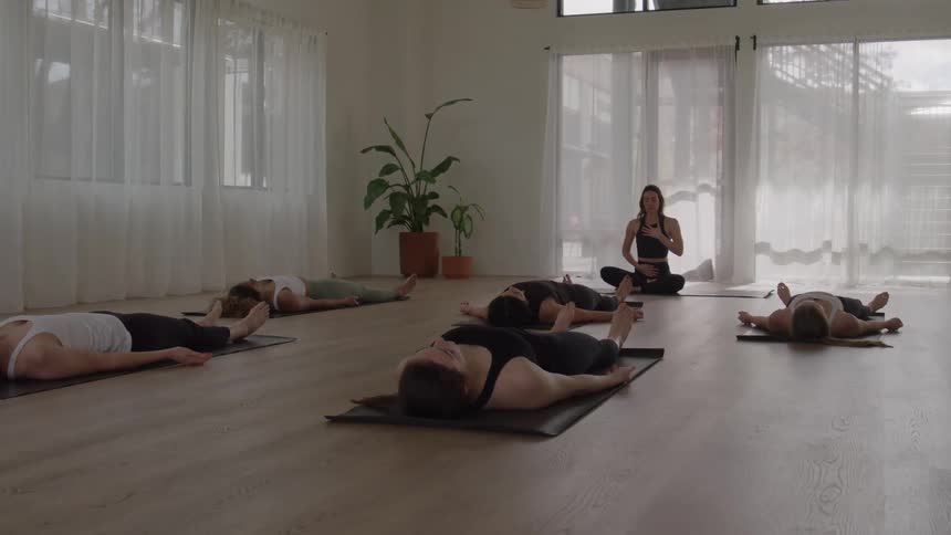 Women are laying on yoga mats in the yoga studio