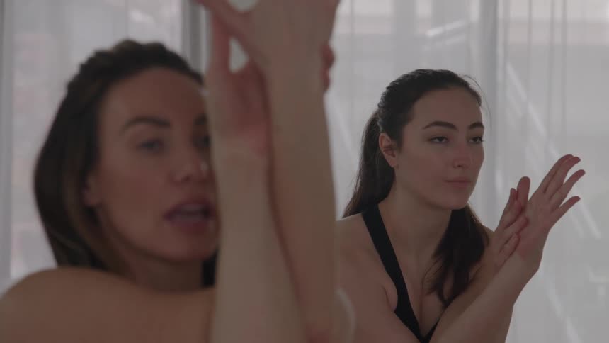 Women cross their arms in front of their faces during a yoga practice