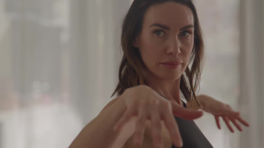 A woman practices yoga doing arm movements slowly