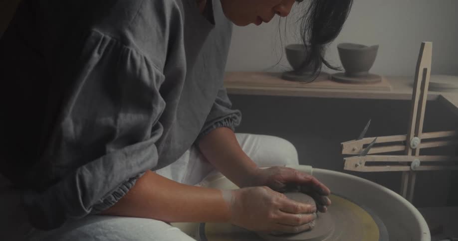 The woman is using a pottery wheel
