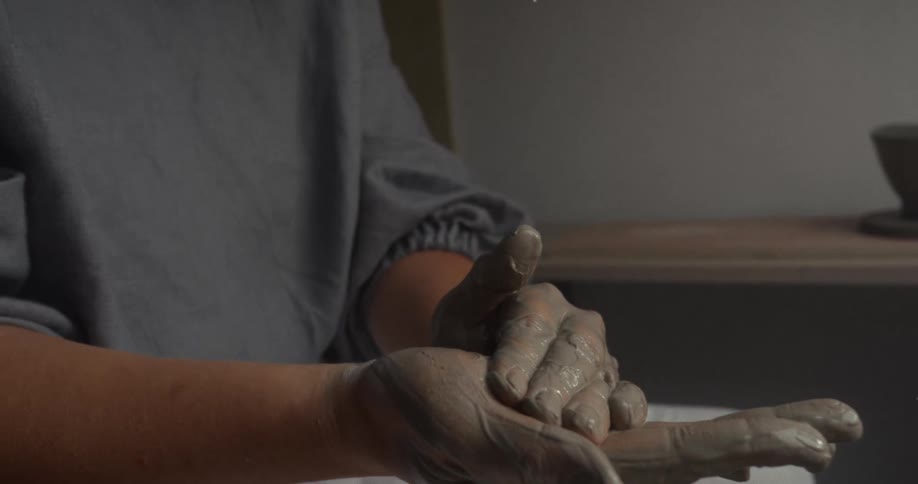 Hands covered in clay shape material during the pottery process