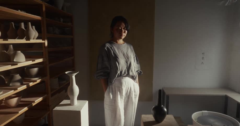 Woman in a studio surrounded by ceramic pieces and natural light