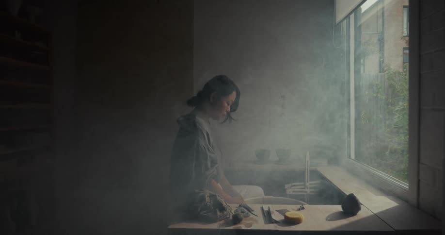 The woman is looking at the pottery wheel in the smoke filled room