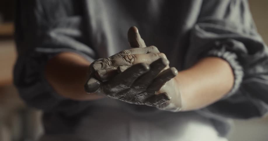 Hands shape wet clay during the creation of a pottery piece