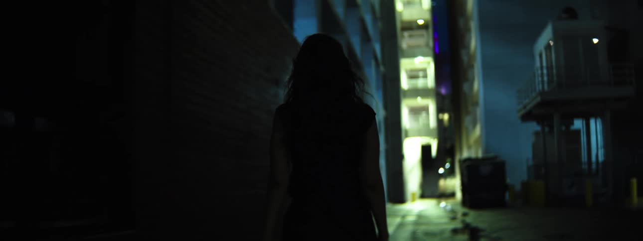 Person walking through an urban alley lit at night