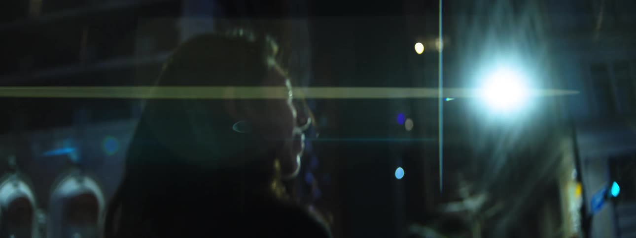 Woman walking at night under bright light in an urban area