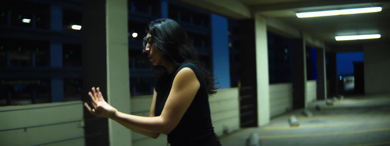 A woman performs an dance while in a parking structure at nighttime