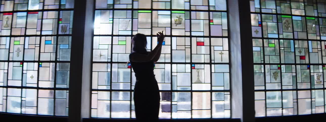 Female silhouette before a mosaic stainedglass wall dances at night