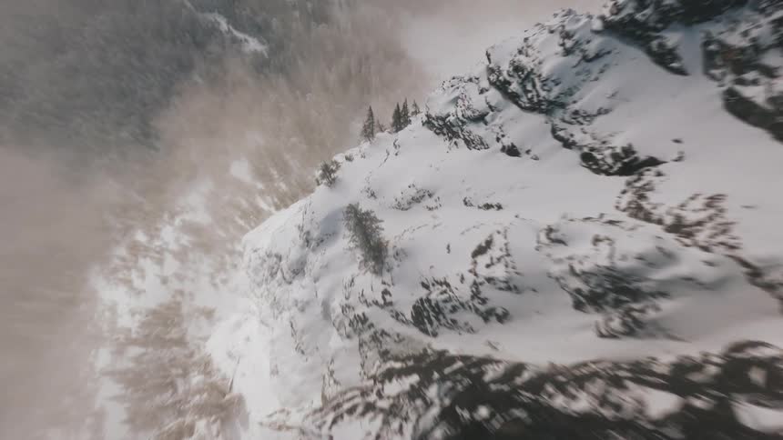 Snowcovered rocky slope with a forest in the background in a mountainous region