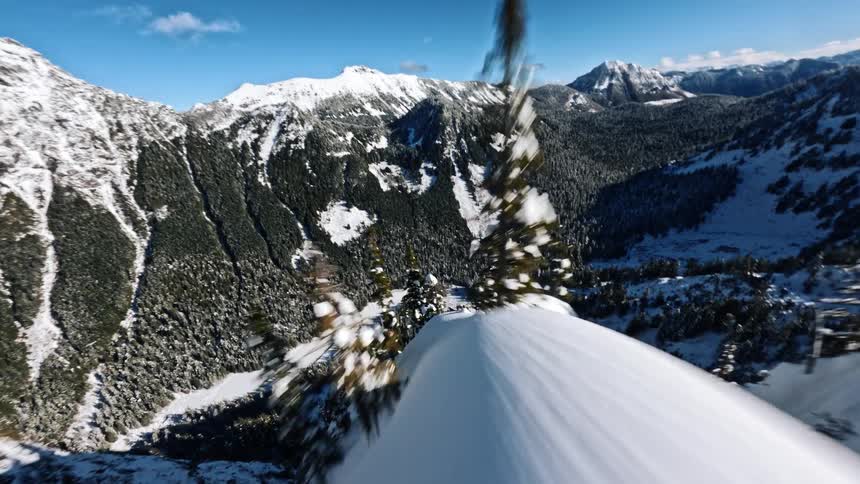 Narrow snowcovered ridge overlooking a valley surrounded by forested mountains