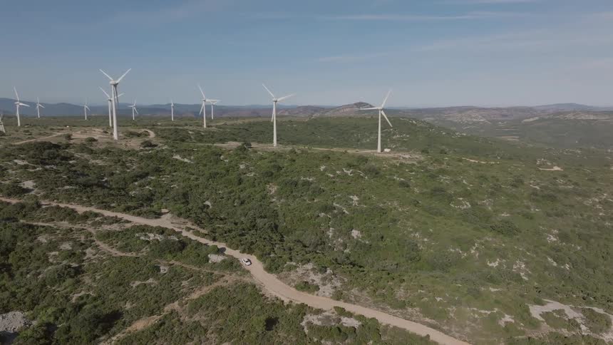 Set of wind turbines spread across vegetationcovered hills under a clear sky