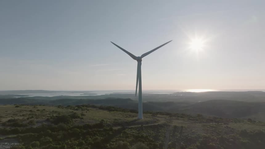 The large windmill spins on the hill