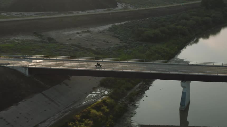 A motorcycle rides over a bridge