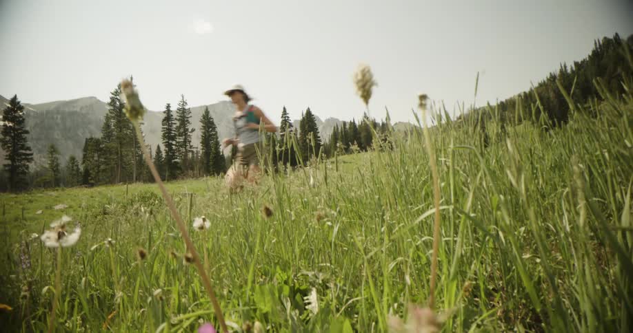 The woman is running by the forest and mountains