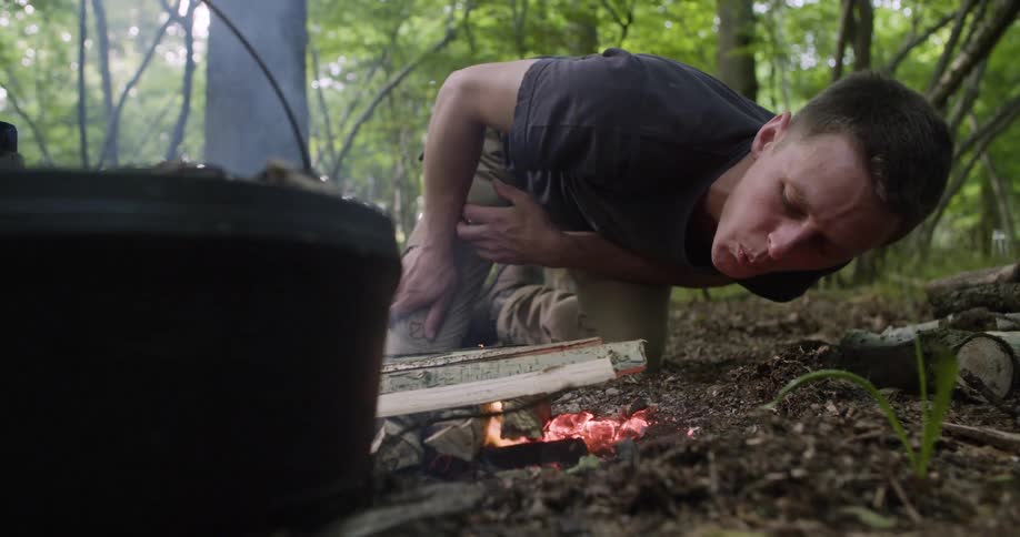The man is starting a campfire