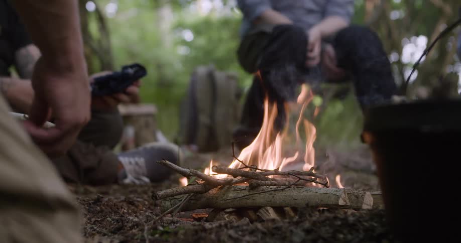 People gathered around a campfire made of branches in an outdoor setting