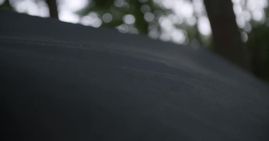 A close view shows a dark tarp gently moving in the wind with bright blurry lights from trees in the background