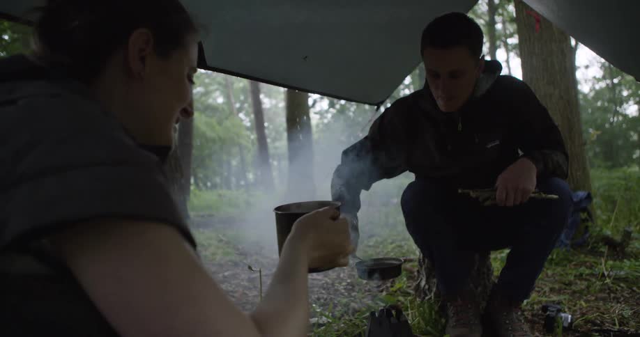 The woman heats a drink at the camp site