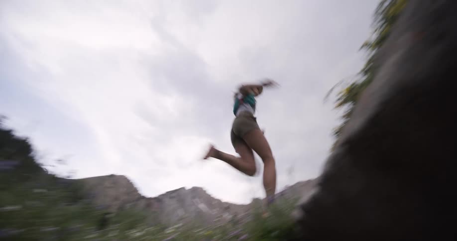 The woman runs and jumps past the mountain