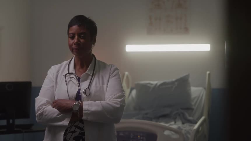 The doctor is standing by the hospital bed