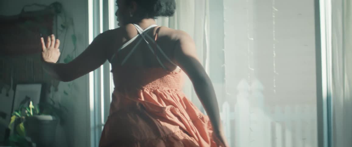 Woman in an orange dress spinning in a dance movement in a bright indoor setting