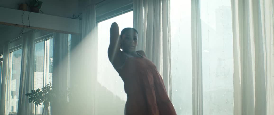 Woman in an orange dress dancing in a naturally lit space