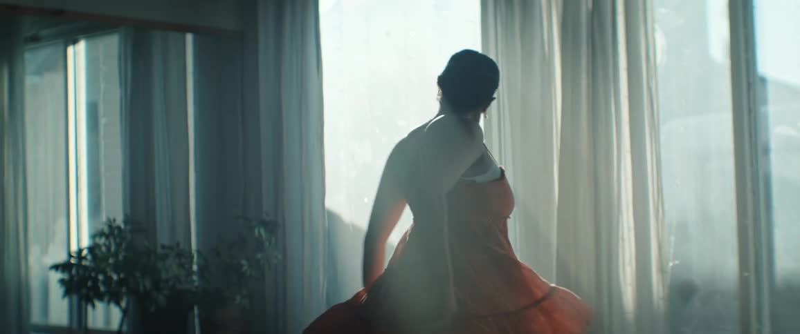 Minority Woman dancing indoors in an orange dress