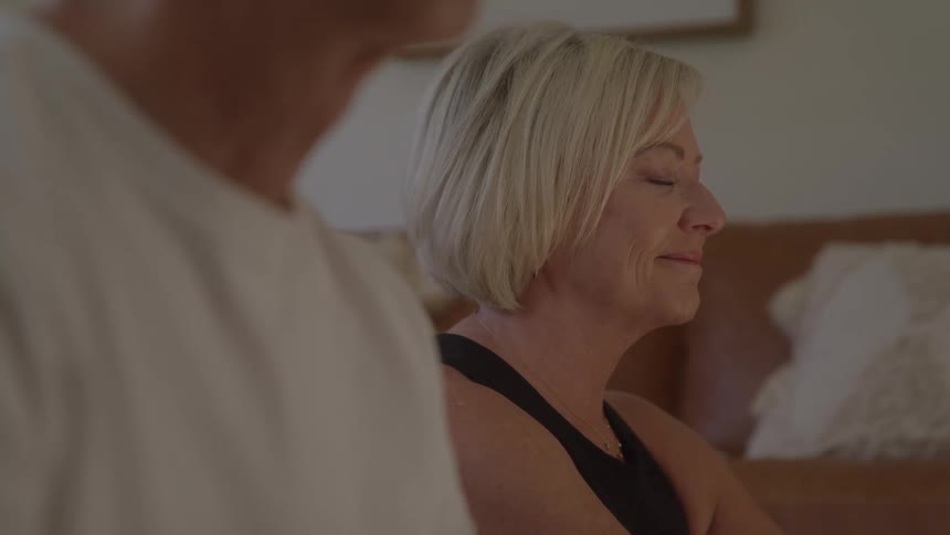 Close up of a middle aged couple doing yoga meditation together in a living room during daytime