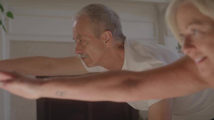 Man extends his arm forward during exercise next to a woman