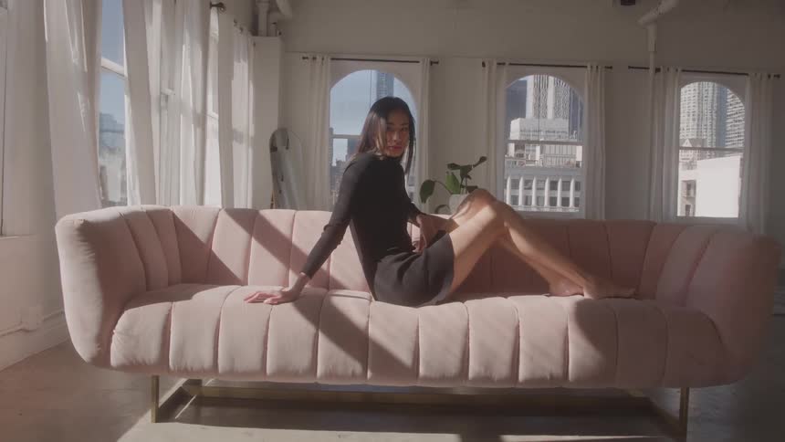 Woman model sitting with legs on pink sofa