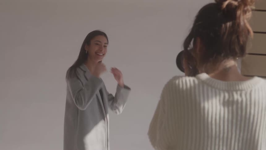 The model is smiling and tossing her hair as her picture is taken