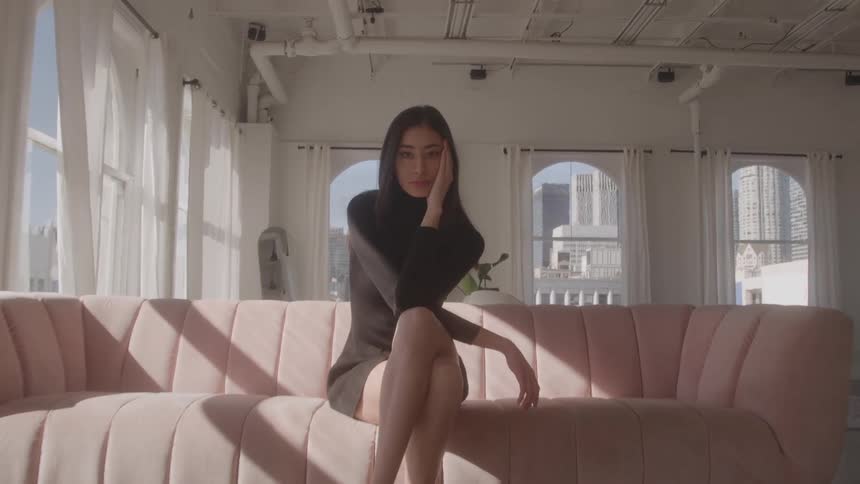 The model is sitting on a pink couch