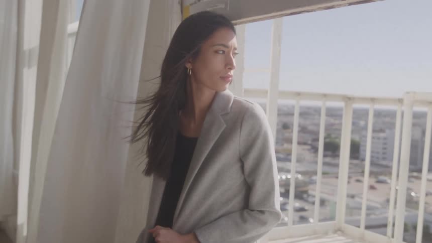 The wind blows the models hair who is posing by the window
