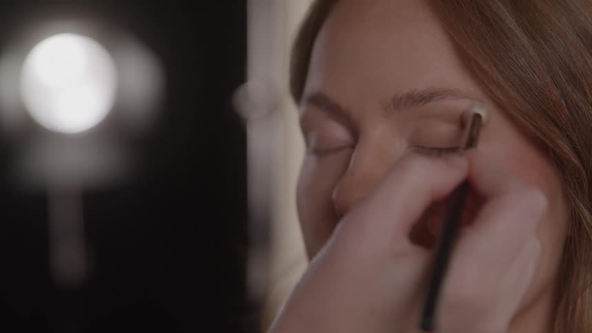 Close up of a young woman getting her face makeup done in a studio