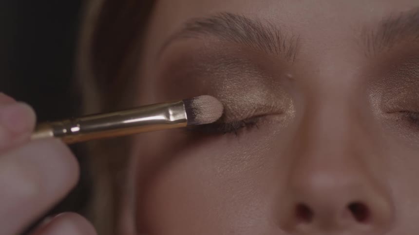 Makeup is being applied to the womans eyelid