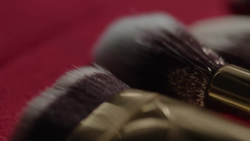 Makeup brushes with golden handles on a red surface
