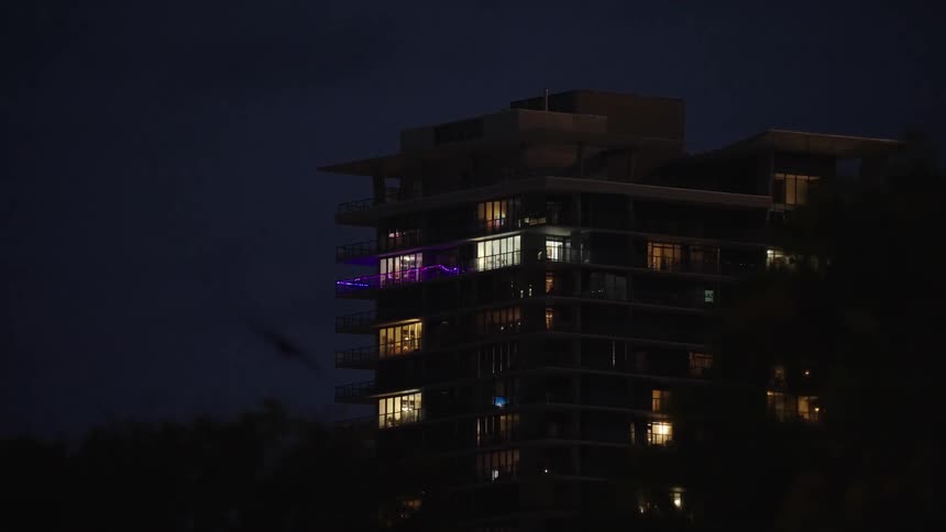 A building at night with lit up windows and birds flying nearby