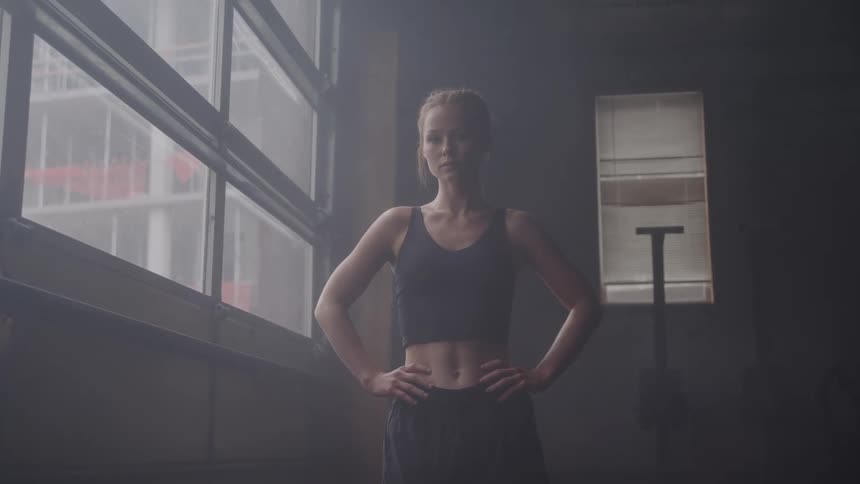 A young woman wearing activewear is at the gym beside a window at midday