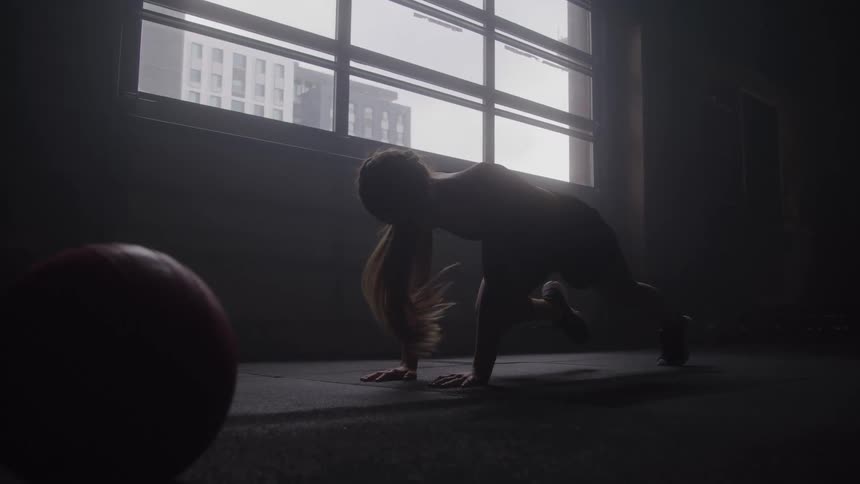 A young woman exercising on the floor in a room during daytime