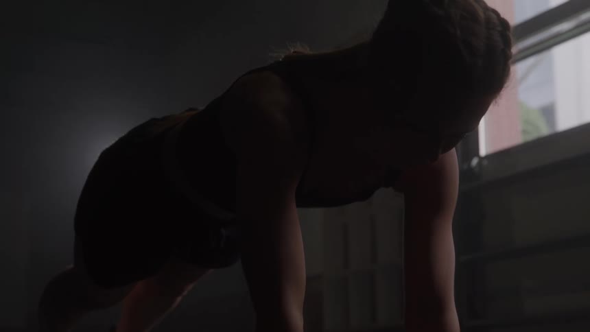 Close up of a young woman exercising on the floor in a room during daytime
