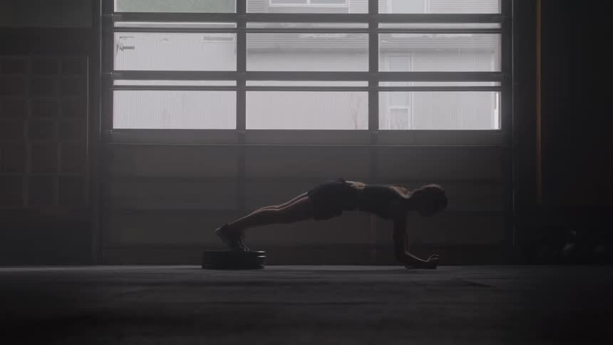 Person training in a plank position supported by one arm in an indoor setting
